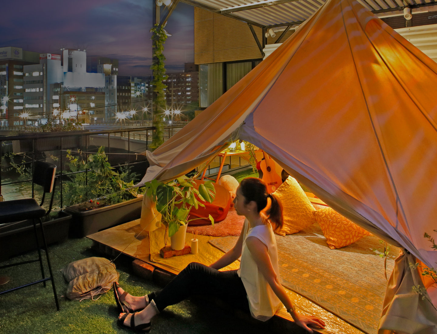 夕焼けを眺める女性とグランピングテント