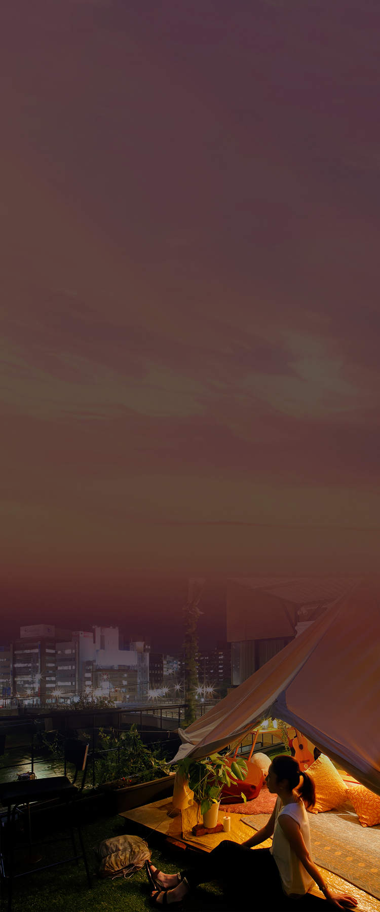 夕焼けを眺める女性とグランピングテント